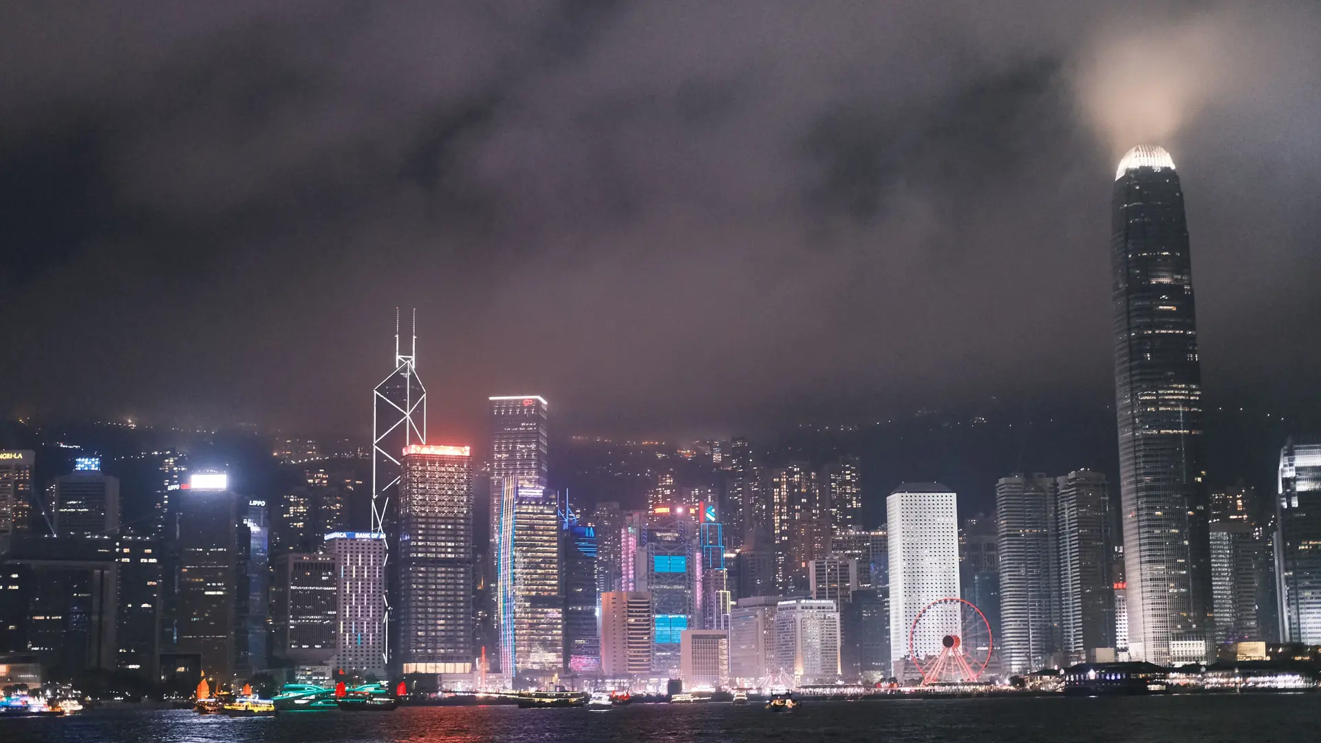 Hong Kong Island at night with cloud around the towers, seen across Victoria Harbour