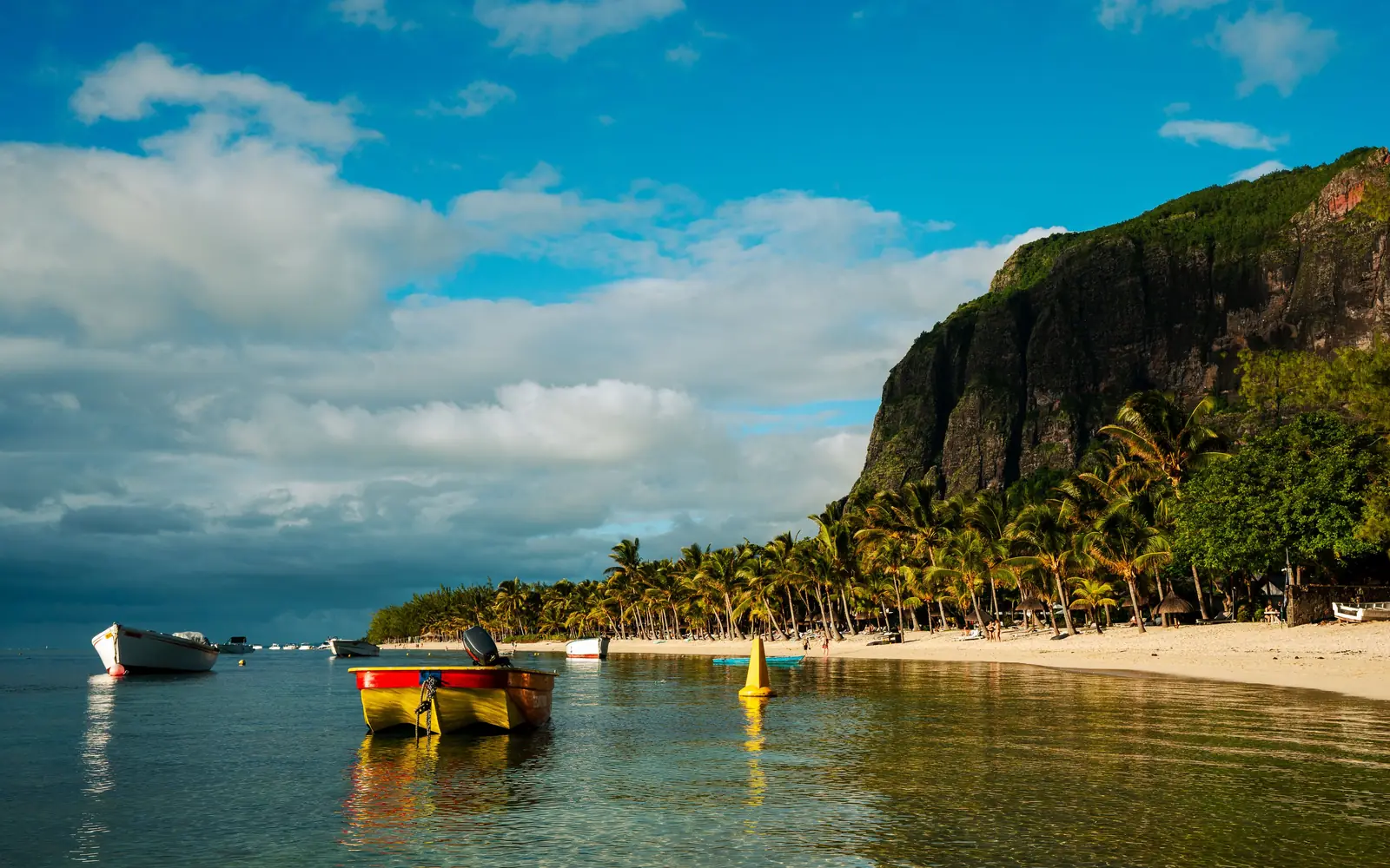 Fishing boats on a calm lagoon below a green headland in Mauritius