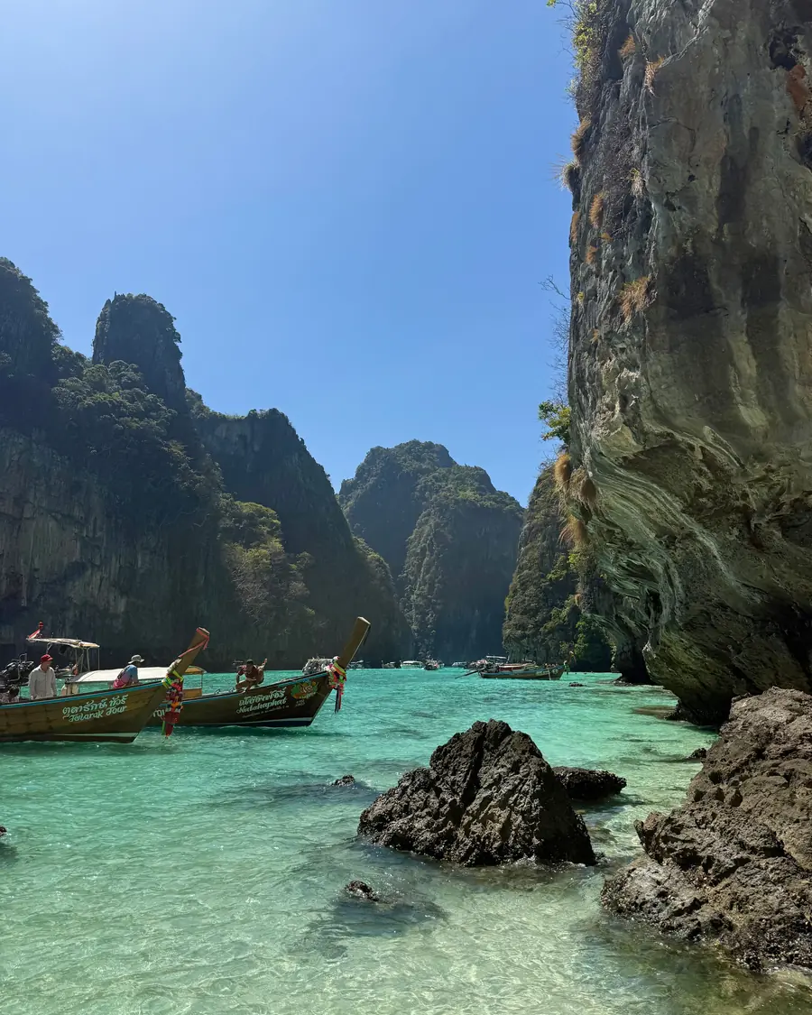 A longtail boat moored below limestone cliffs at the Phi Phi islands, Thailand
