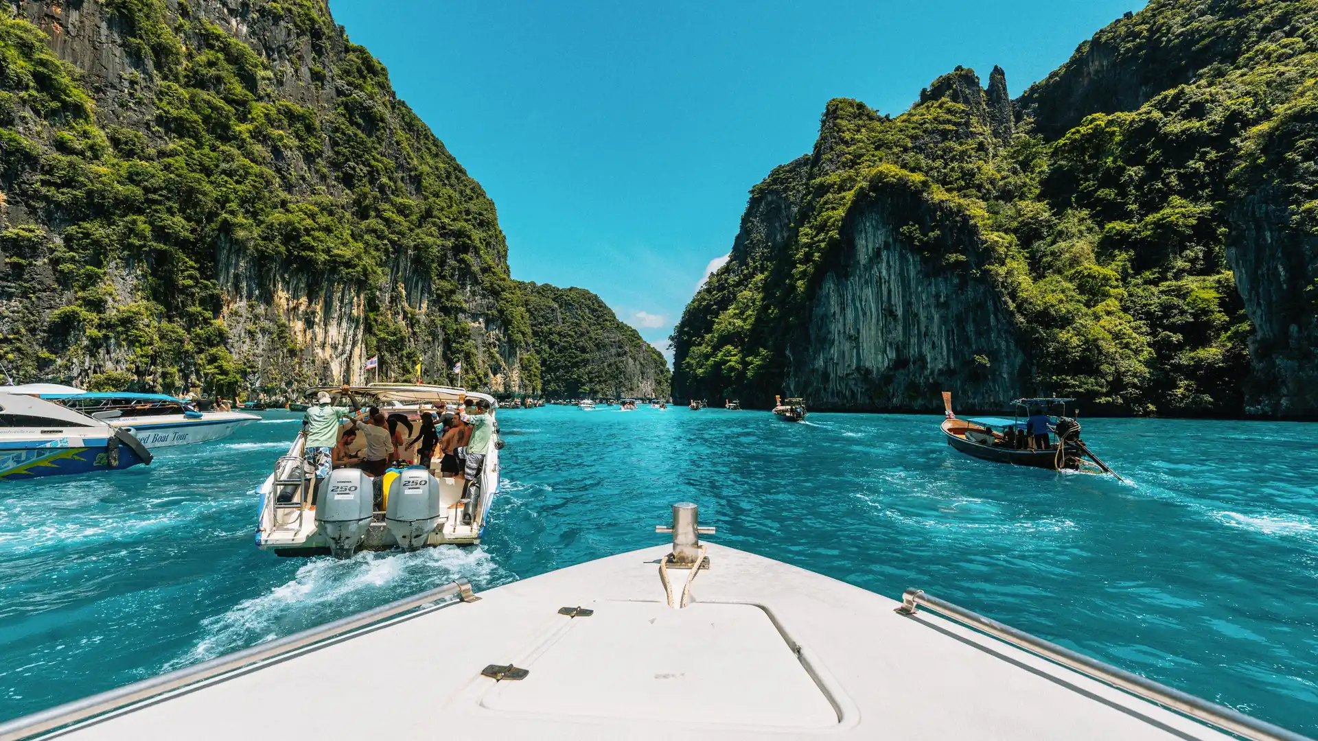 The bow of a speedboat heading between the limestone cliffs of Krabi, Thailand